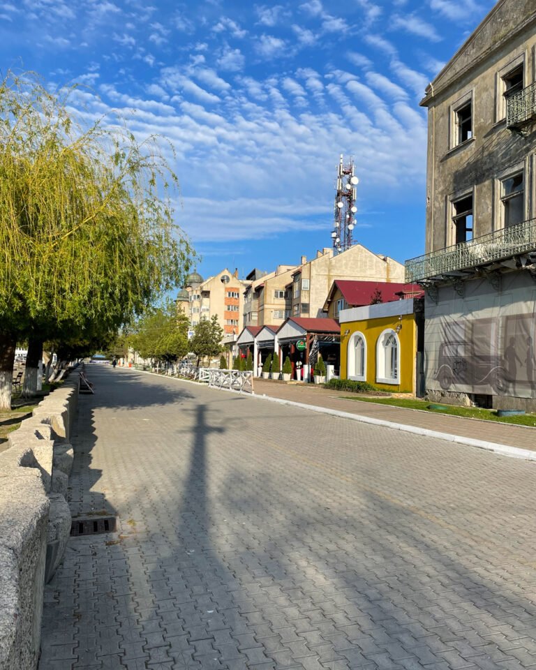 Stradă pietonală, clădiri, cer albastru cu nori.